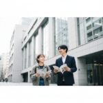 東京アニメーションカレッジ専門学校の進路選びをイメージした、校舎の前で希望に満ちた表情を浮かべる日本人学生の男女