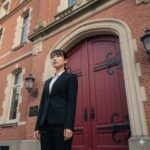 吹き替えの名門としての歴史を持つマウスプロモーションの象徴的な赤い扉の前に立つ日本人声優志望者