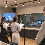 声優養成所の収録スタジオで設備や実技授業を見学する日本人女性